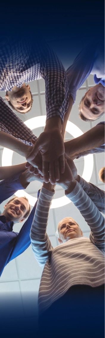 Five team members standing in a circle stacking hands together in unity