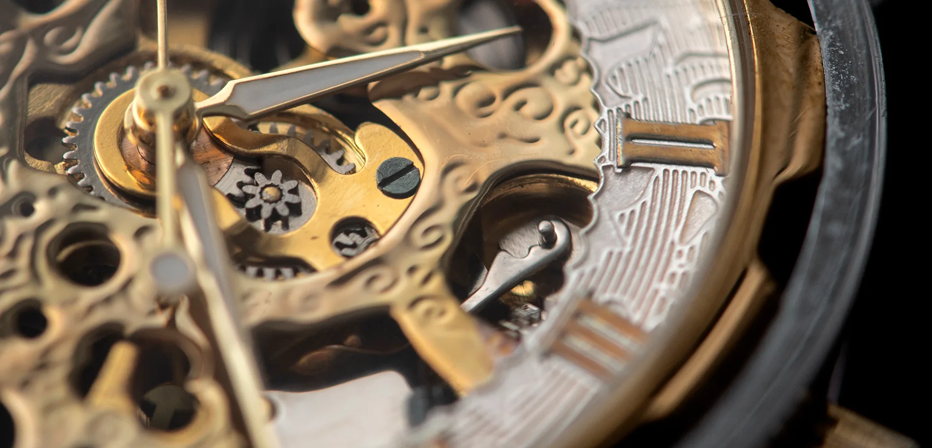 Close-up of the gold gears and engraved dial of a mechanical watch