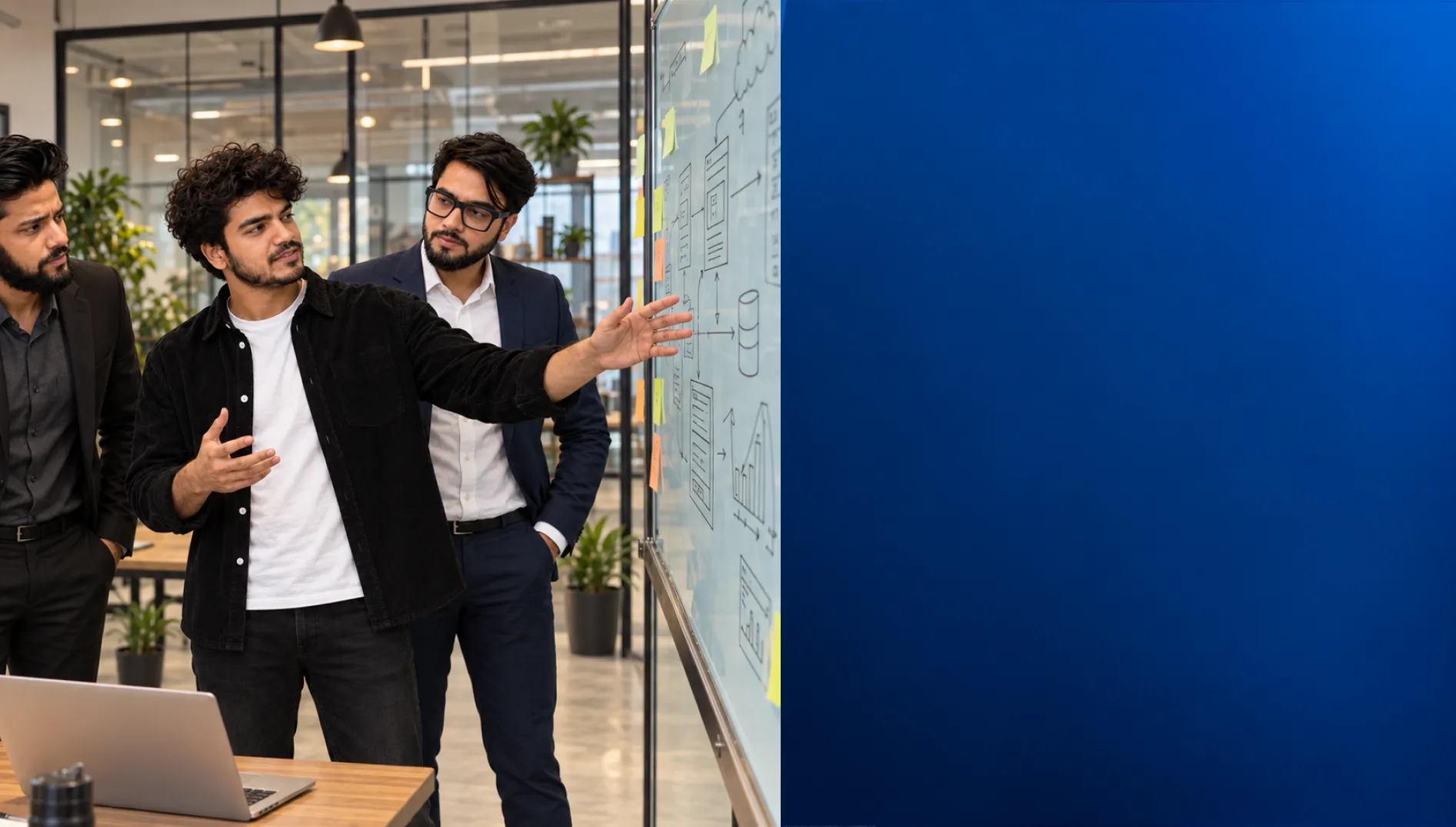 Three colleagues discussing a system diagram sketched on an office whiteboard