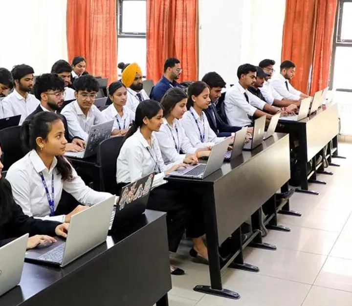 College lecturer speaking to students seated at laptops
