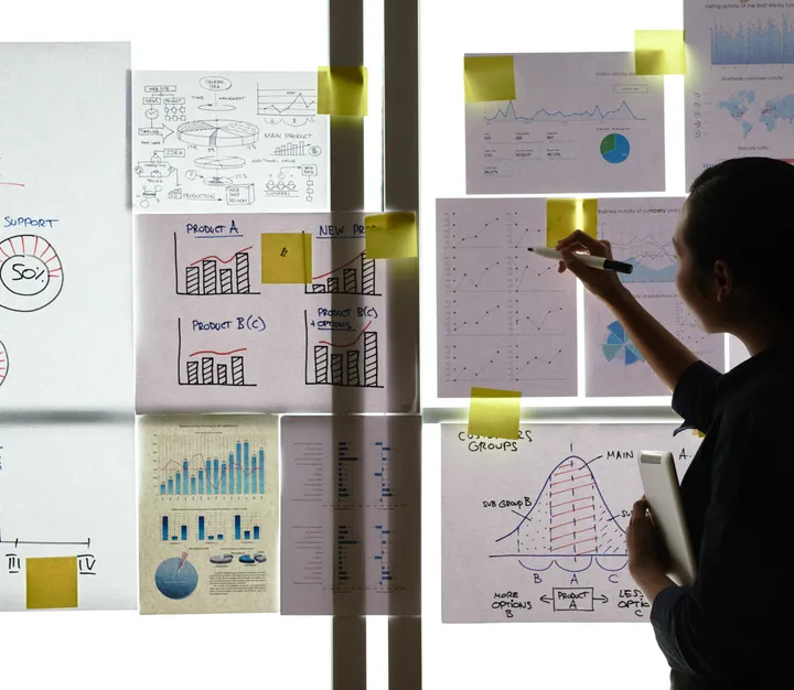 Teacher writing on a wall of charts and sticky notes