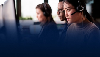 Two professionals wearing headsets working at computers in a call centre