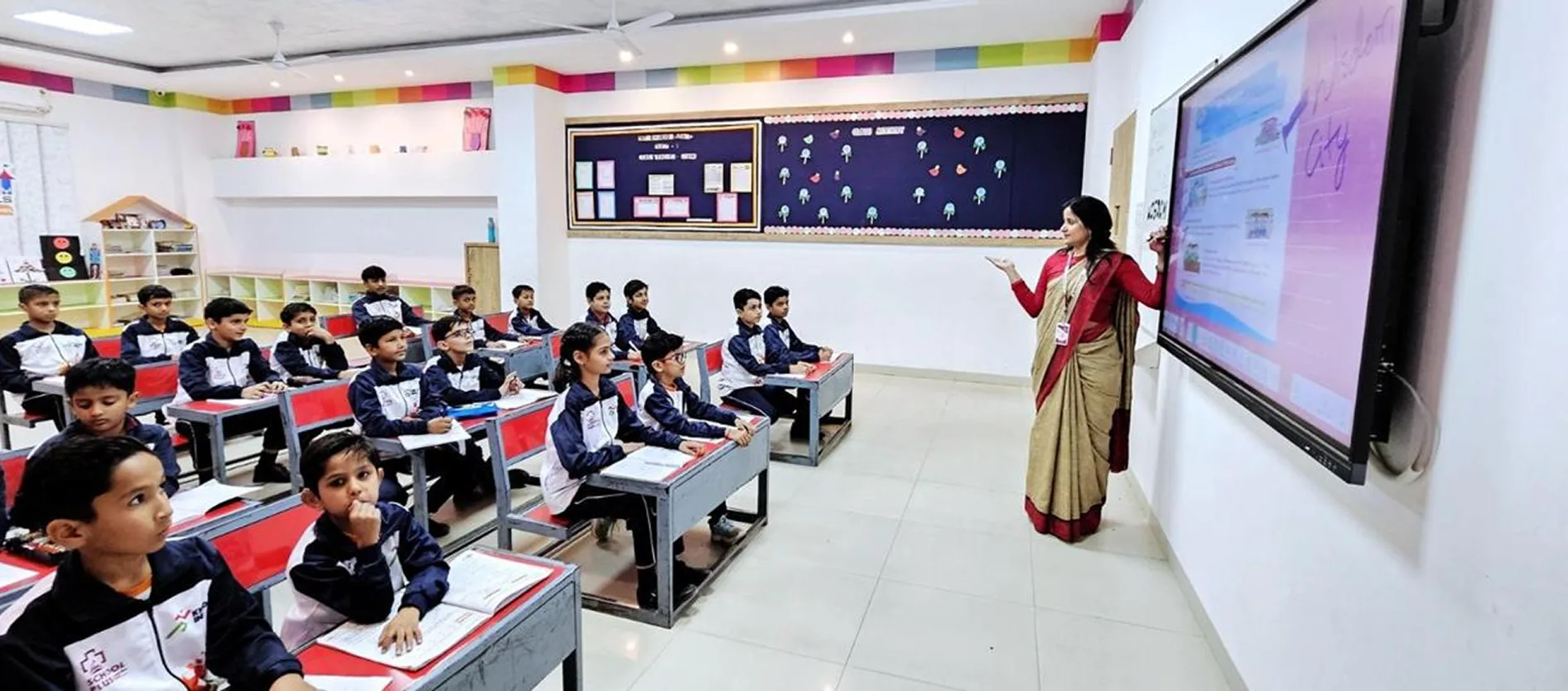 Teacher presenting a lesson on an interactive smart board to a class of students in uniform