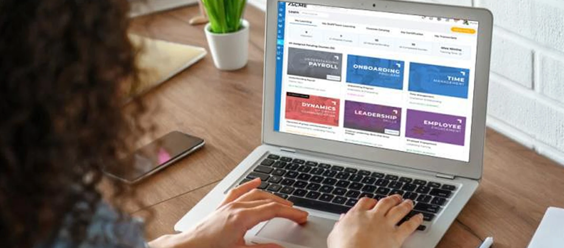 Person at a laptop browsing online training courses such as onboarding, leadership and time management