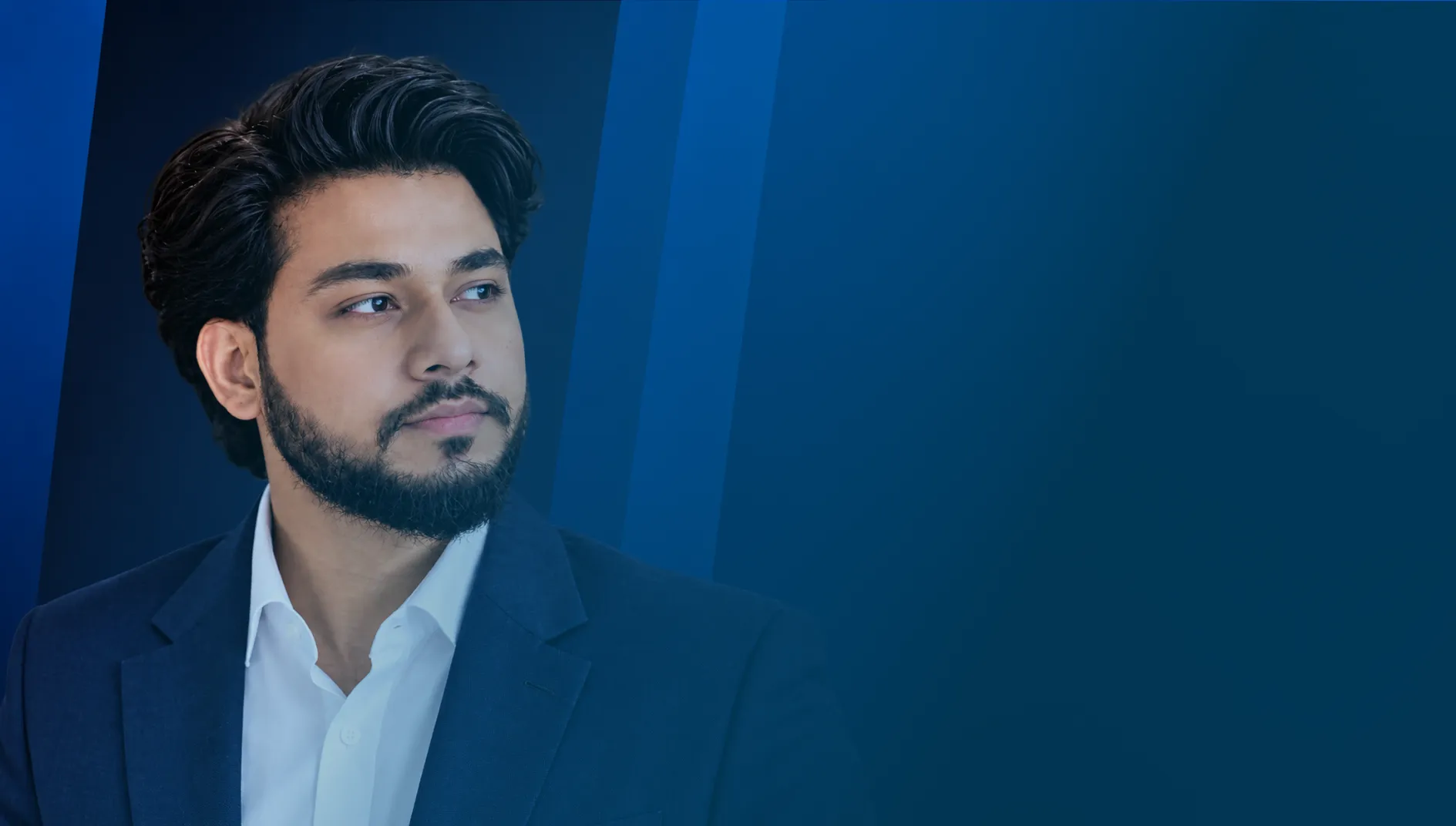 Young professional in a navy suit looking into the distance against a blue background