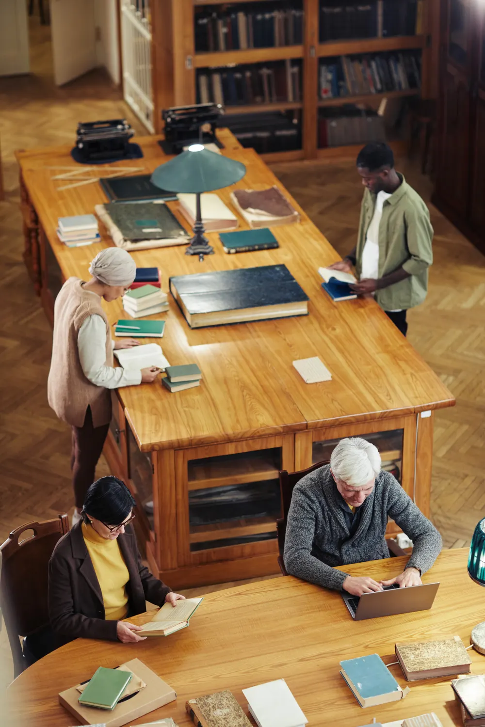 Students and readers studying at long wooden tables in a library