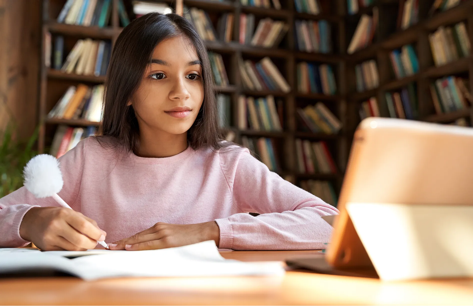 Schoolgirl studying at a desk in a library