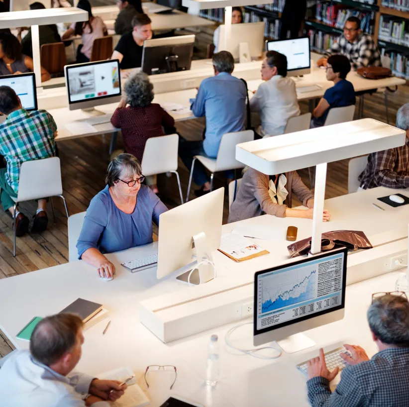People working at computers in a bright open-plan library workspace