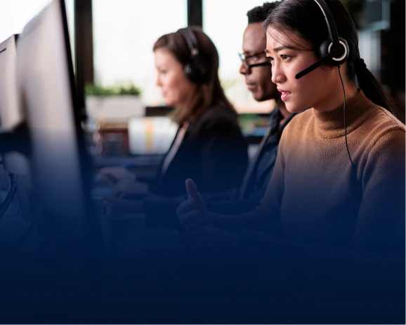 Three customer support agents wearing headsets working at computers in an office