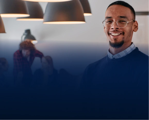 Smiling young man with glasses in a modern co-working space with warm pendant lights